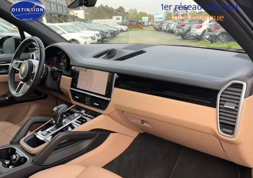 Vue intérieure côté passager du tableau de bord beige et noir du Porsche Cayenne 2023 avec écran tactile et volant cuir.