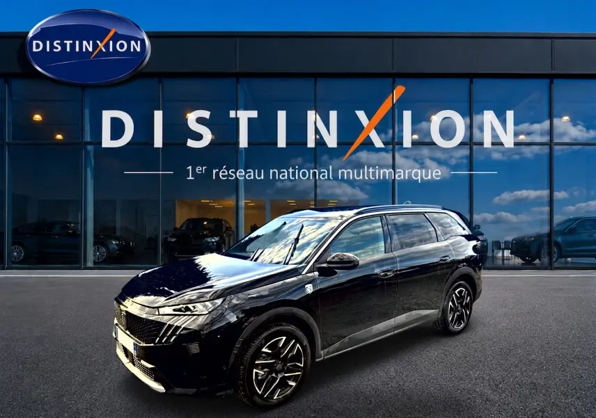 Peugeot 5008 Hybrid 145 GT noir en 3/4 avant droit, avec jantes alliage et vitres surteintées devant un showroom Distinxion.