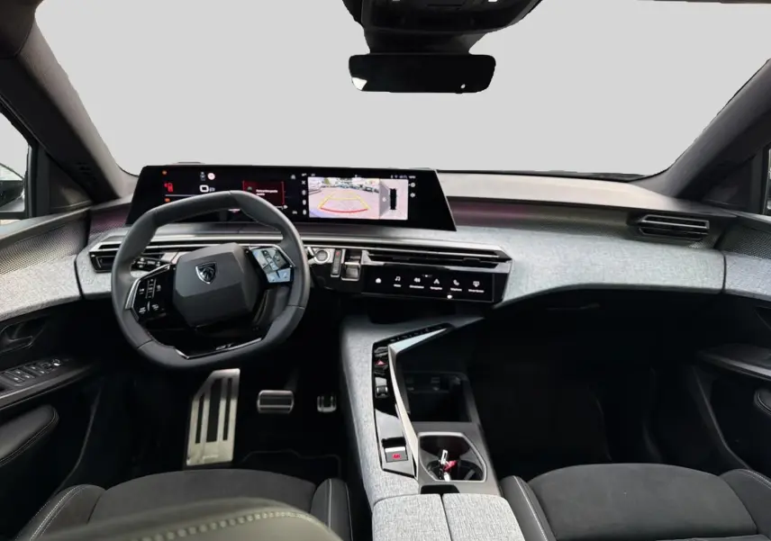 Vue intérieure avant du Peugeot 5008 Hybrid 145 GT e-dcs6 2025, tableau de bord moderne gris clair avec écran tactile large.
