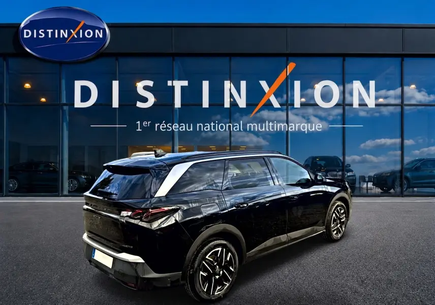 Vue 3/4 arrière droite d’un Peugeot 5008 Hybrid 145 GT noir, avec jantes alu et becquet arrière visible.