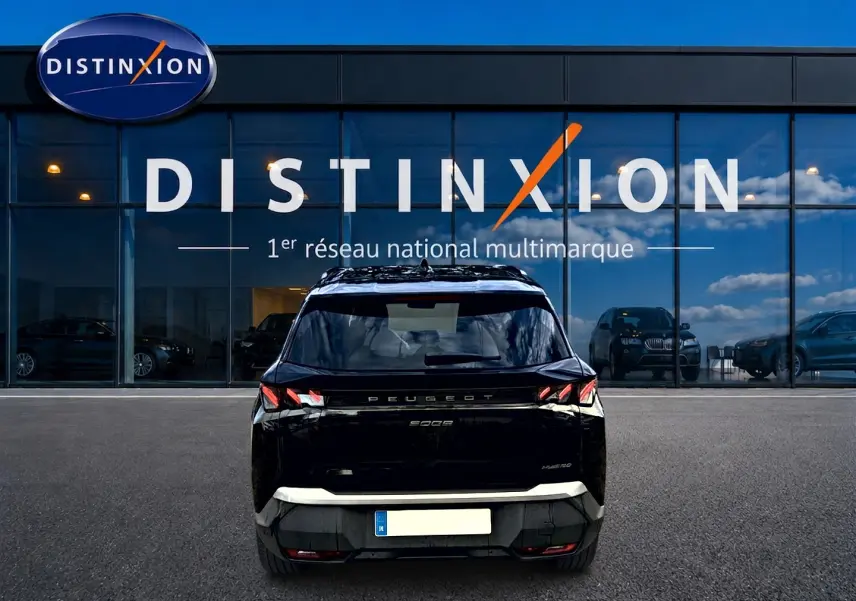Vue arrière d'un Peugeot 5008 Hybrid 145 GT noir garé devant une vitrine avec logo Distinxion.