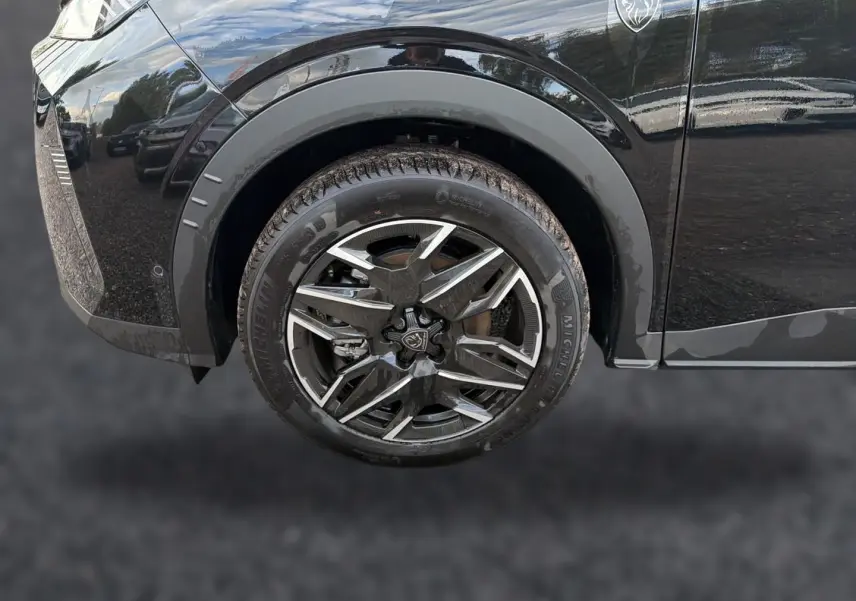 Gros plan sur la roue avant droite noire du Peugeot 5008 Hybrid 145 GT avec jante alu au design moderne.