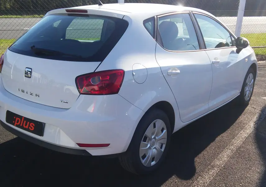 SEAT Ibiza Business blanche vue en 3/4 arrière droit, avec feux arrière rouges et jantes acier simples.