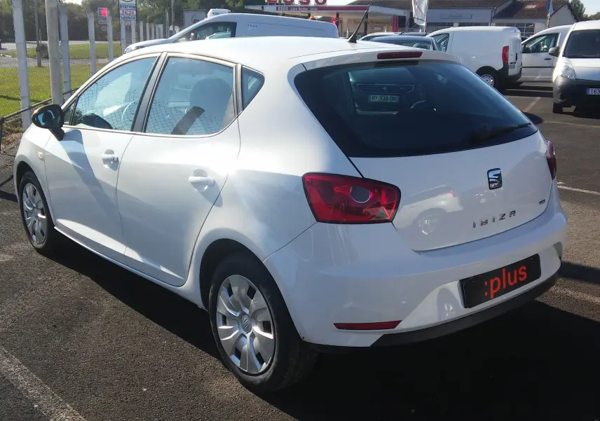 Vue 3/4 arrière droite d'une SEAT Ibiza Business blanche garée sur un parking en extérieur.