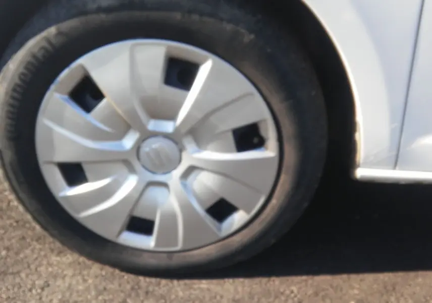 Gros plan sur la roue avant gauche blanche d'une SEAT Ibiza Business 2015 avec enjoliveur d'origine.