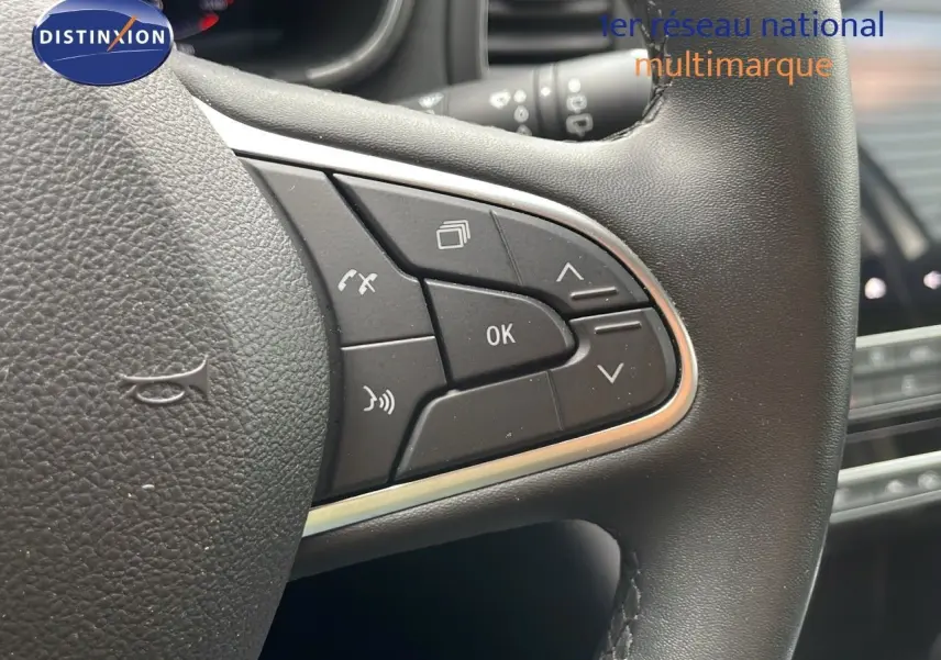 Gros plan sur les commandes au volant en cuir noir de la Renault Mégane Break 2024, version diesel gris Highland Metal.