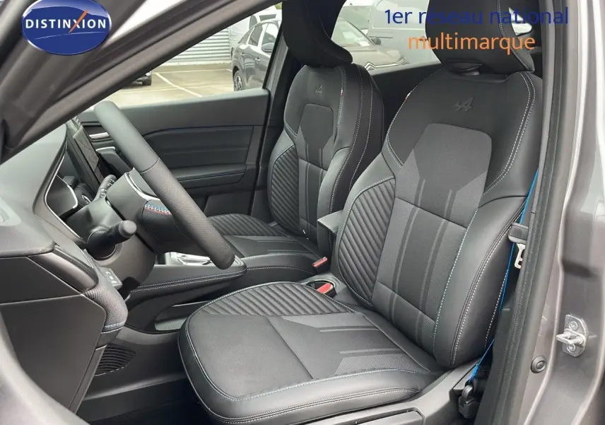 Vue intérieure côté conducteur du Renault Symbioz gris cassiopée métal, mettant en valeur les sièges sport noirs avec surpiqûres bleues et logo Alpine.