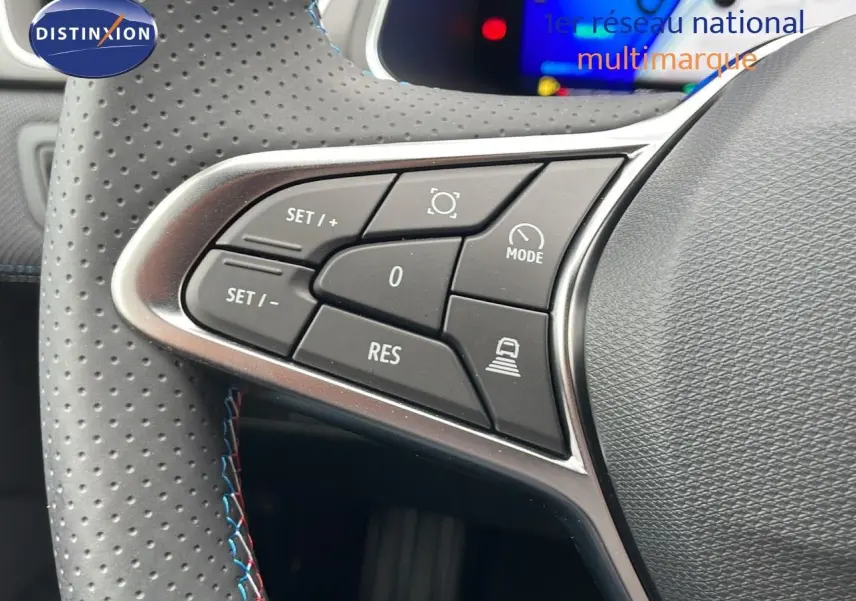 Gros plan sur les commandes de régulateur de vitesse au volant perforé d'une Renault Symbioz gris cassiopée.