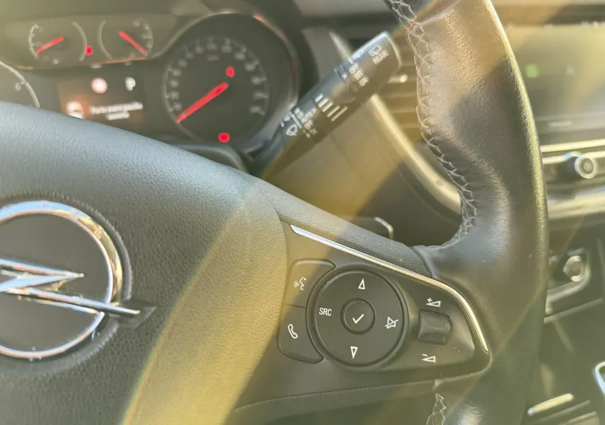 Gros plan sur le volant en cuir noir de l'Opel Grandland X 2019, avec commandes intégrées et tableau de bord flou en arrière-plan.