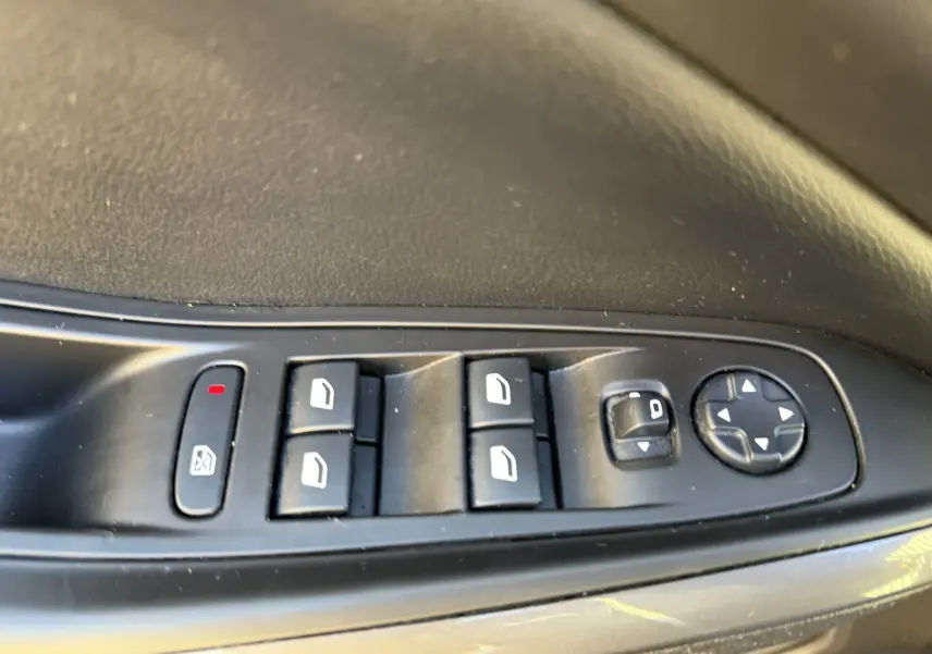 Commandes électriques des vitres et rétroviseurs sur la porte côté conducteur d'un Opel Grandland X gris quartz de 2019.