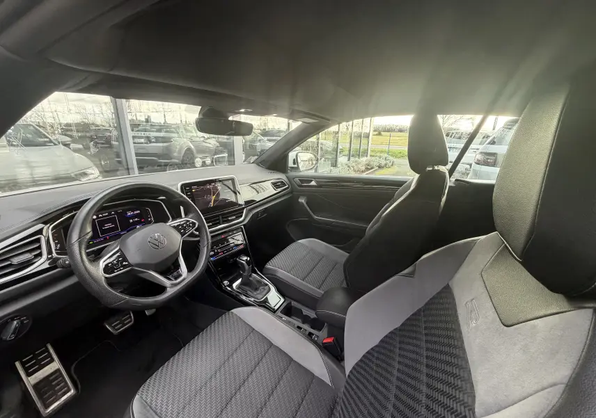 Vue intérieure côté conducteur du Volkswagen T-Roc Cabriolet 2022, sièges R-Line en tissu noir et gris avec volant multifonction.