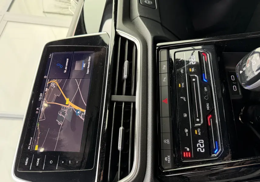 Vue rapprochée de la console centrale du Volkswagen T-Roc Cabriolet blanc 2022, avec écran tactile et commandes climatisation digitales.