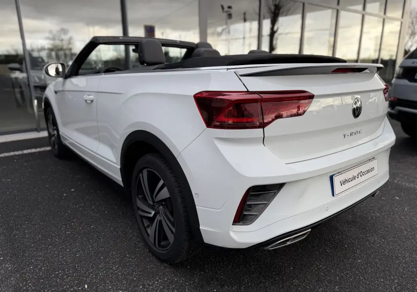 Vue 3/4 arrière droite d'un Volkswagen T-Roc Cabriolet blanc 2022 avec toit ouvert et finition R-Line.