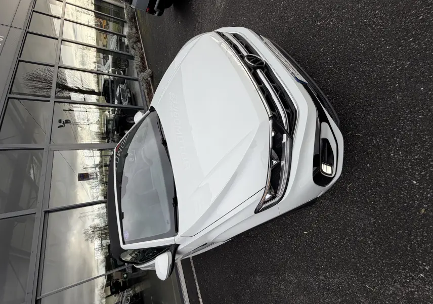 Vue 3/4 avant droit d'un Volkswagen T-Roc Cabriolet blanc 2022 avec calandre R-Line et toit ouvert.