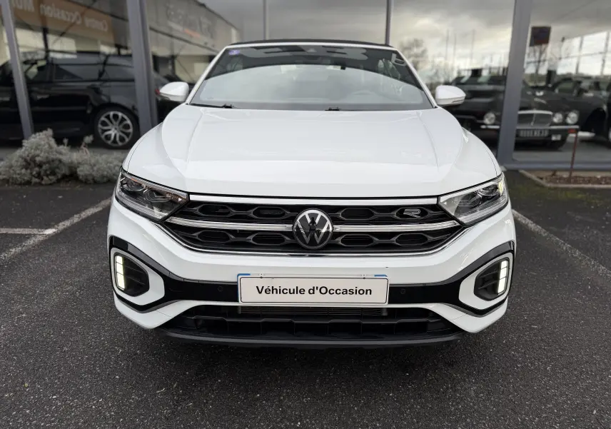 Vue frontale d'un Volkswagen T-Roc Cabriolet blanc 2022 avec calandre R-Line et feux LED allumés.