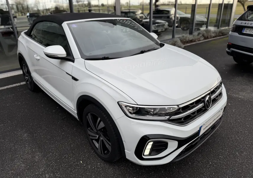 Vue 3/4 avant d’un Volkswagen T-Roc Cabriolet blanc 2022 avec toit noir fermé et finition R-Line.