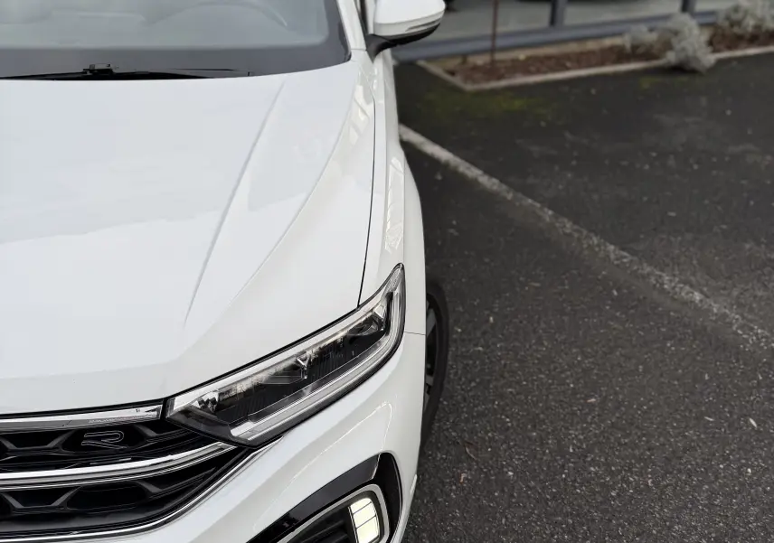 Vue 3/4 avant droit du Volkswagen T-Roc Cabriolet blanc 2022, mettant en valeur ses phares LED et la calandre R-Line.