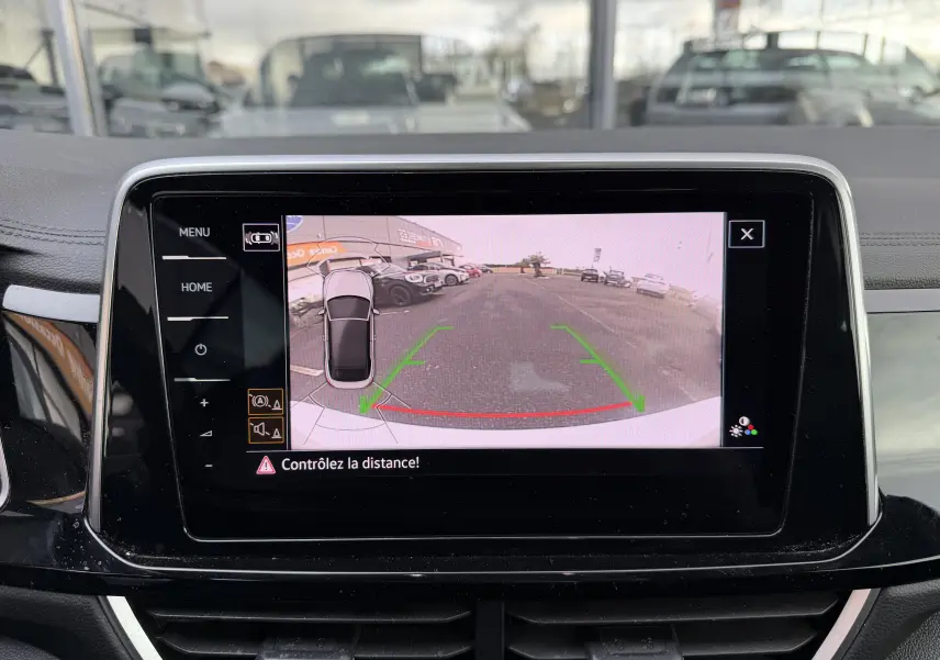 Écran de caméra de recul dans un Volkswagen T-Roc Cabriolet blanc, vue arrière avec lignes de guidage vertes et rouges.