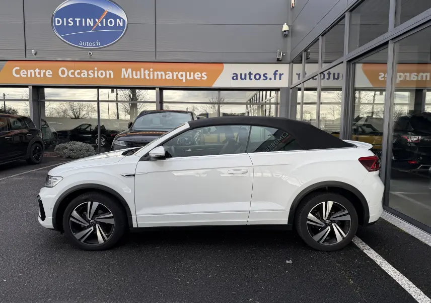 Vue de profil côté gauche d'un Volkswagen T-Roc Cabriolet blanc avec toit noir en position fermée, version R-Line 2022.