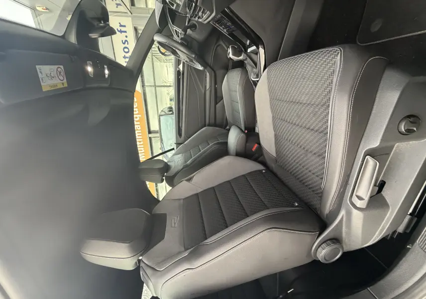 Vue intérieure côté conducteur du Volkswagen T-Roc Cabriolet 2022, sièges sport noirs avec surpiqûres et logo R-Line.