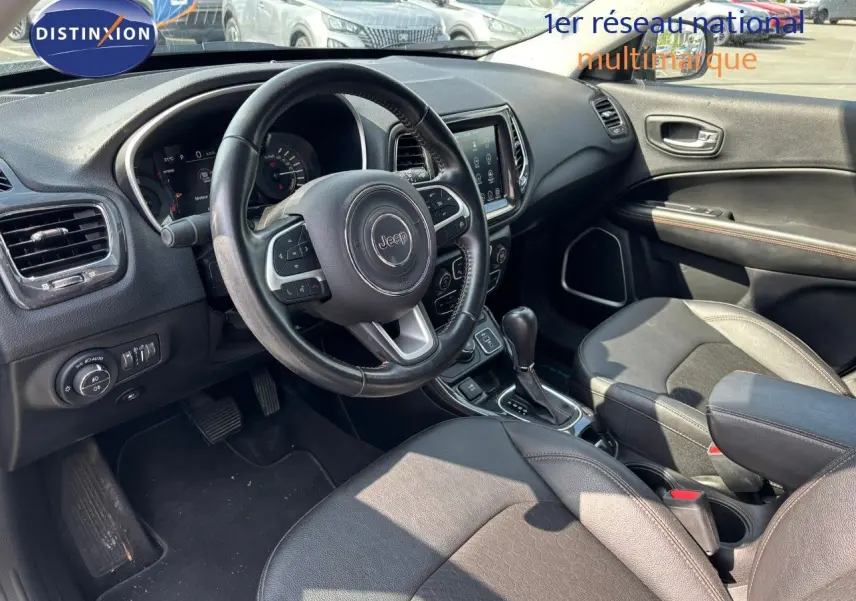 Vue intérieure avant droite du Jeep Compass blanc 2021, volant cuir, console centrale avec boîte auto et écran tactile.