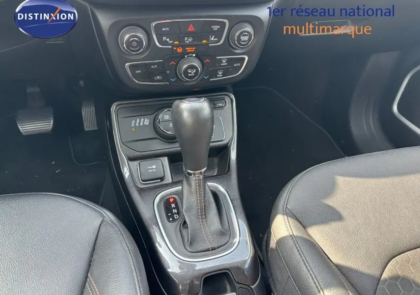 Vue rapprochée de la console centrale du Jeep Compass hybride rechargeable 2021, avec levier de vitesse automatique et sièges cuir noirs.