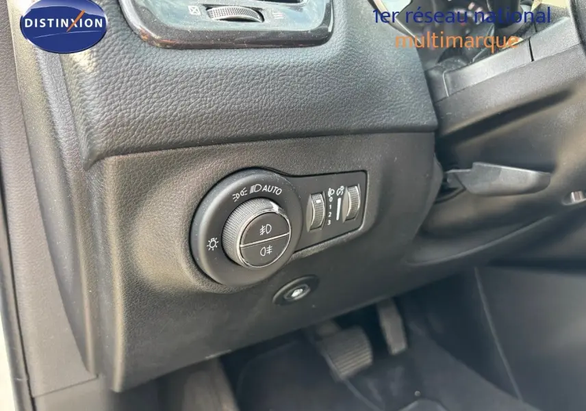 Gros plan sur le bouton de réglage des phares à gauche du tableau de bord du Jeep Compass blanc hybride rechargeable.