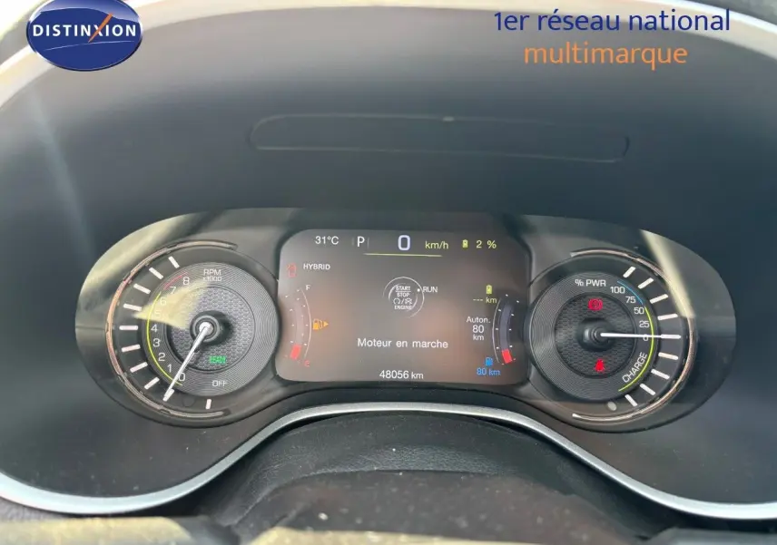 Vue rapprochée du tableau de bord numérique du Jeep Compass blanc, affichant les compteurs hybrides et la vitesse à 0 km/h.