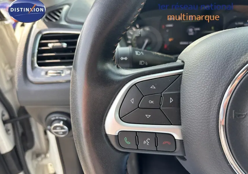 Gros plan sur le volant côté gauche du Jeep Compass blanc 2021, avec commandes intégrées et tableau de bord partiel visible.