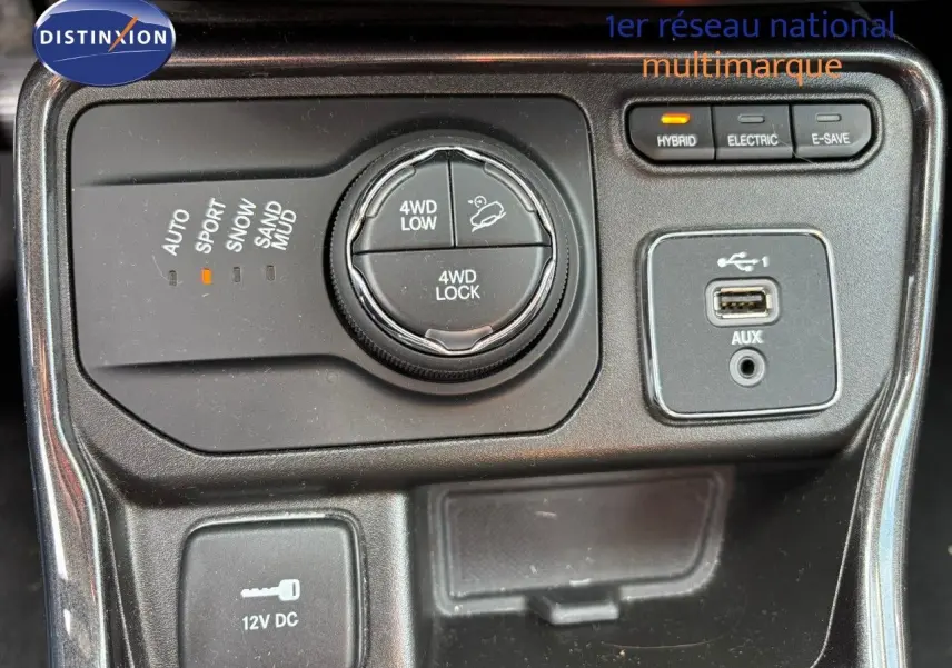 Vue rapprochée du tableau de bord du Jeep Compass hybride, montrant la molette 4WD et les boutons de mode de conduite.