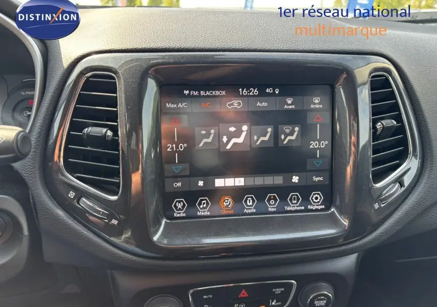 Vue rapprochée de l'écran tactile central du tableau de bord du Jeep Compass blanc, affichant les réglages de climatisation.