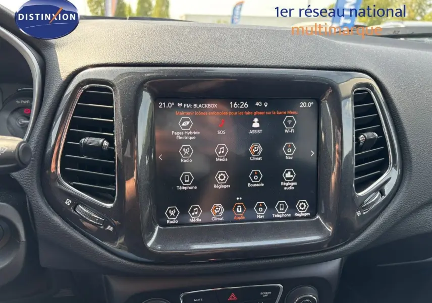 Vue rapprochée du tableau de bord du Jeep Compass blanc 2021, écran tactile central avec commandes climatisation et multimédia.