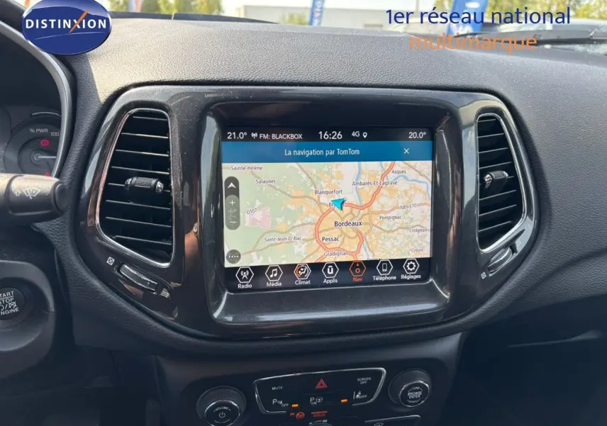 Vue rapprochée du tableau de bord du Jeep Compass blanc 2021, mettant en valeur l’écran tactile avec navigation GPS active.
