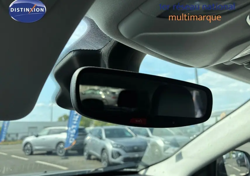 Vue intérieure centrée sur le rétroviseur intérieur d’un Jeep Compass blanc, avec reflet du pare-brise et extérieur flou.