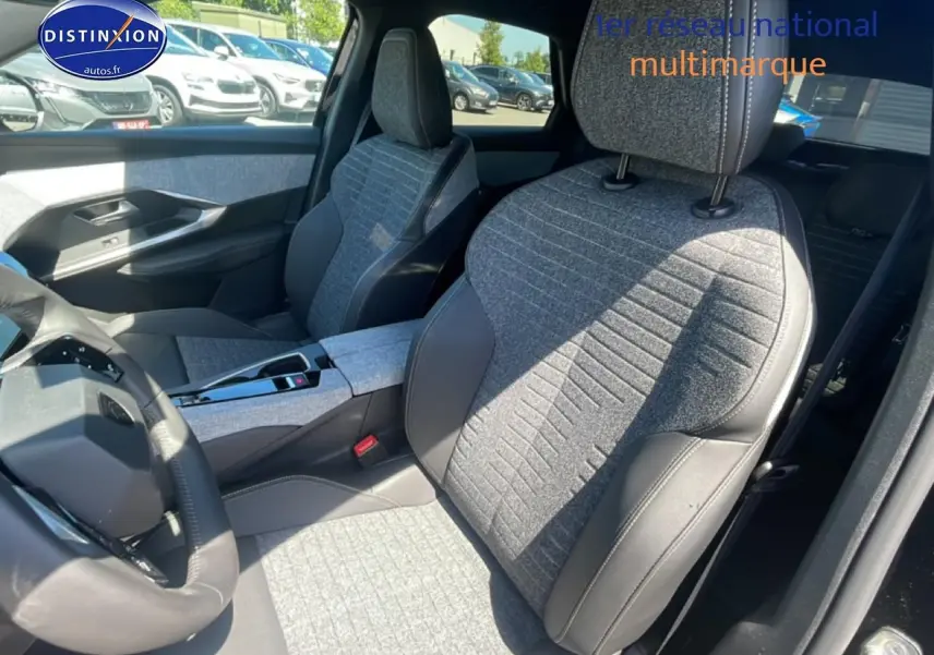 Vue intérieure côté conducteur du Peugeot 3008 noir 2025, sièges tissu gris avec surpiqûres et volant cuir multifonction.