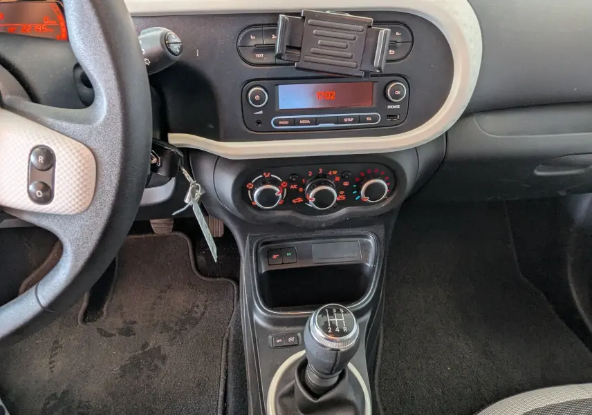 Vue intérieure centrée sur la console centrale et levier de vitesses manuel d'une Renault Twingo III noire de 2019.