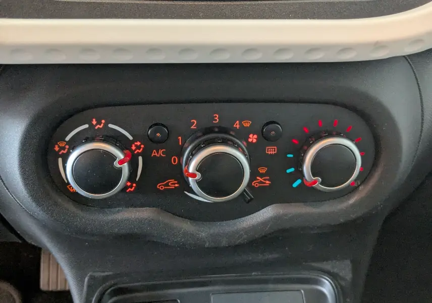 Gros plan sur les commandes de climatisation du tableau de bord d’une Renault Twingo III noire, version 2019.