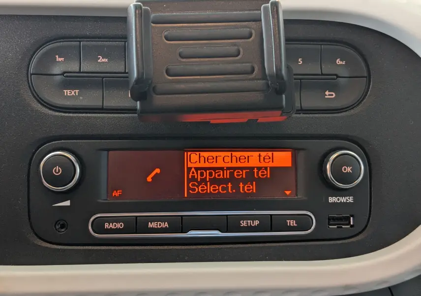 Tableau de bord de Renault Twingo III noir, affichage orange du système multimédia avec options téléphone visibles.