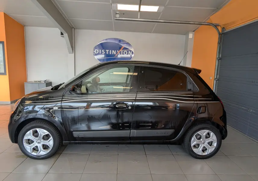 Profil droit d'une Renault Twingo III noire 2019 avec bandes blanches décoratives, en intérieur showroom.