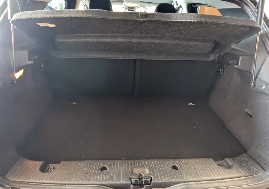 Coffre ouvert vu de l'arrière d'une Renault Twingo III noire, montrant l'espace de chargement vide avec cache-bagages relevé.