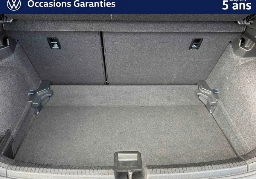 Coffre vide vu de face d'une Volkswagen Polo 2025, revêtement gris et fixations visibles sur les côtés.