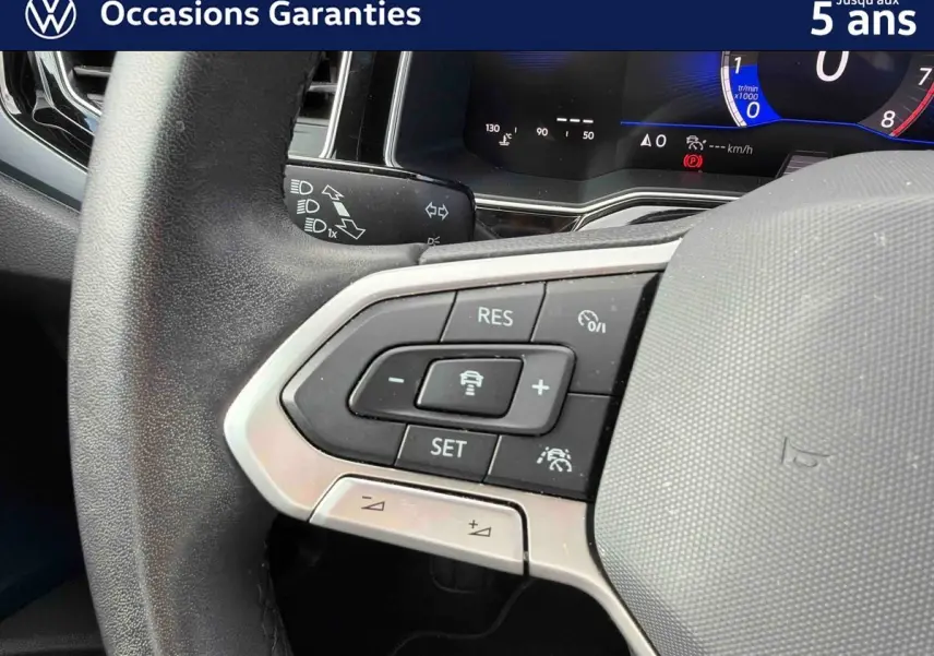 Gros plan sur le volant multifonctions noir de la Volkswagen Polo 2025, avec commandes de régulateur adaptatif visibles.