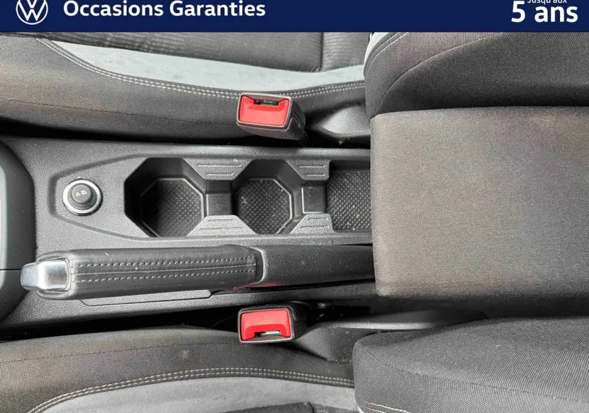 Vue plongeante sur la console centrale noire de la Volkswagen Polo 2025 avec frein à main et deux porte-gobelets.
