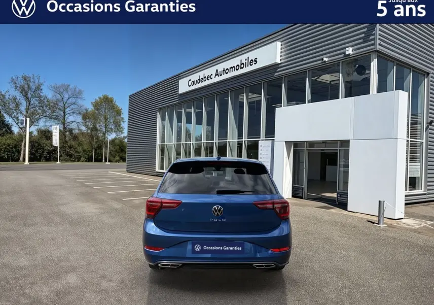 Vue arrière d'une Volkswagen Polo 2025 bleu récif métallisée, avec toit noir et vitres arrière surteintées, stationnée devant un showroom.