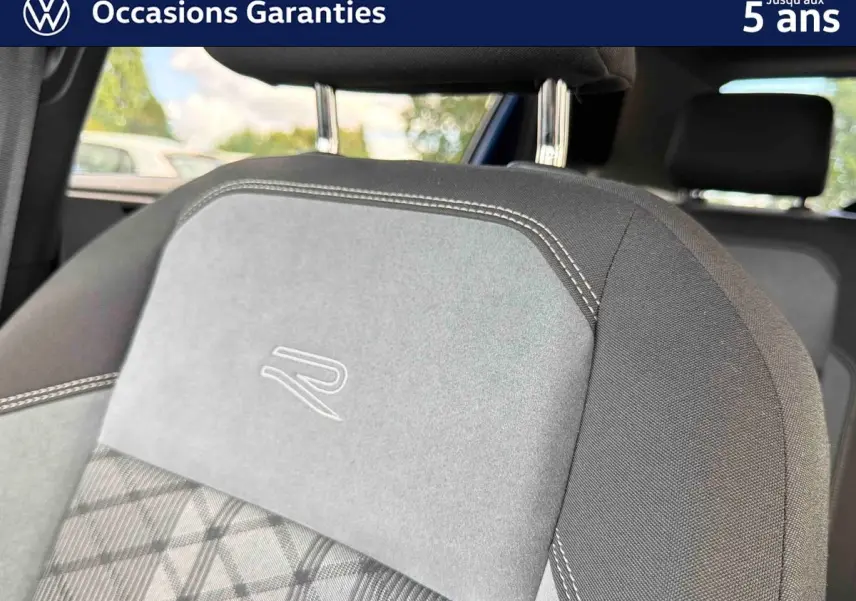 Détail du siège avant gris avec logo R brodé, sur Volkswagen Polo 2025, intérieur visible en arrière-plan.