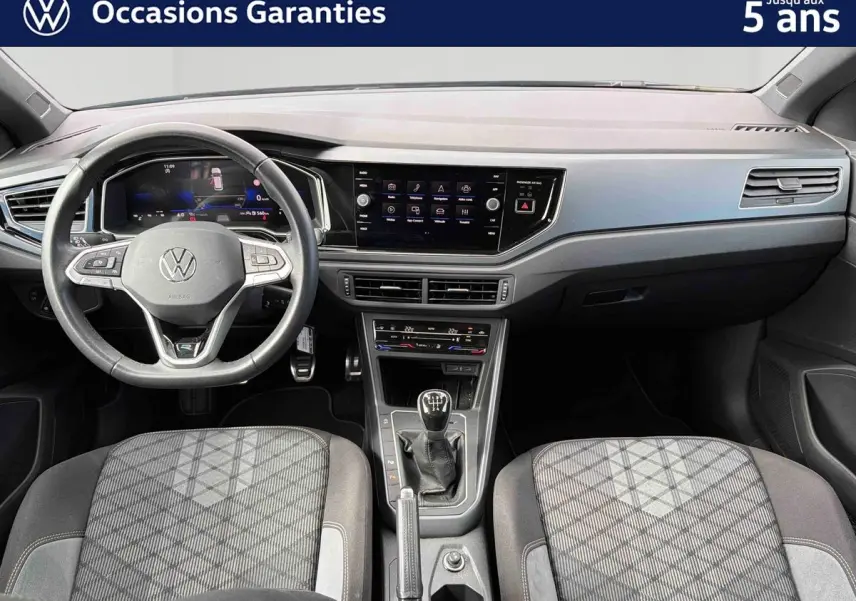 Vue intérieure avant du tableau de bord et volant cuir d’une Volkswagen Polo 2025 avec boîte manuelle et écran tactile central.