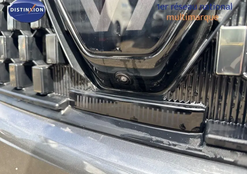 Gros plan sur la calandre noire et la caméra avant du Renault Austral gris schiste métal avec toit noir.