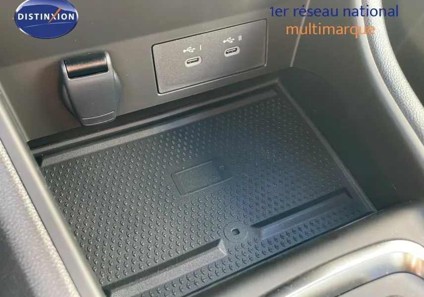 Gros plan sur la console centrale du Renault Captur E-Tech Hybrid 2025, montrant la zone de recharge sans fil et ports USB.