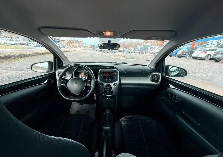Intérieur noir de la Peugeot 108 2018, vue frontale du tableau de bord avec volant et console centrale visibles.