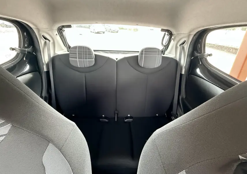 Vue intérieure arrière du Peugeot 108 noir, montrant les sièges arrière avec appuie-têtes à motif à carreaux gris.